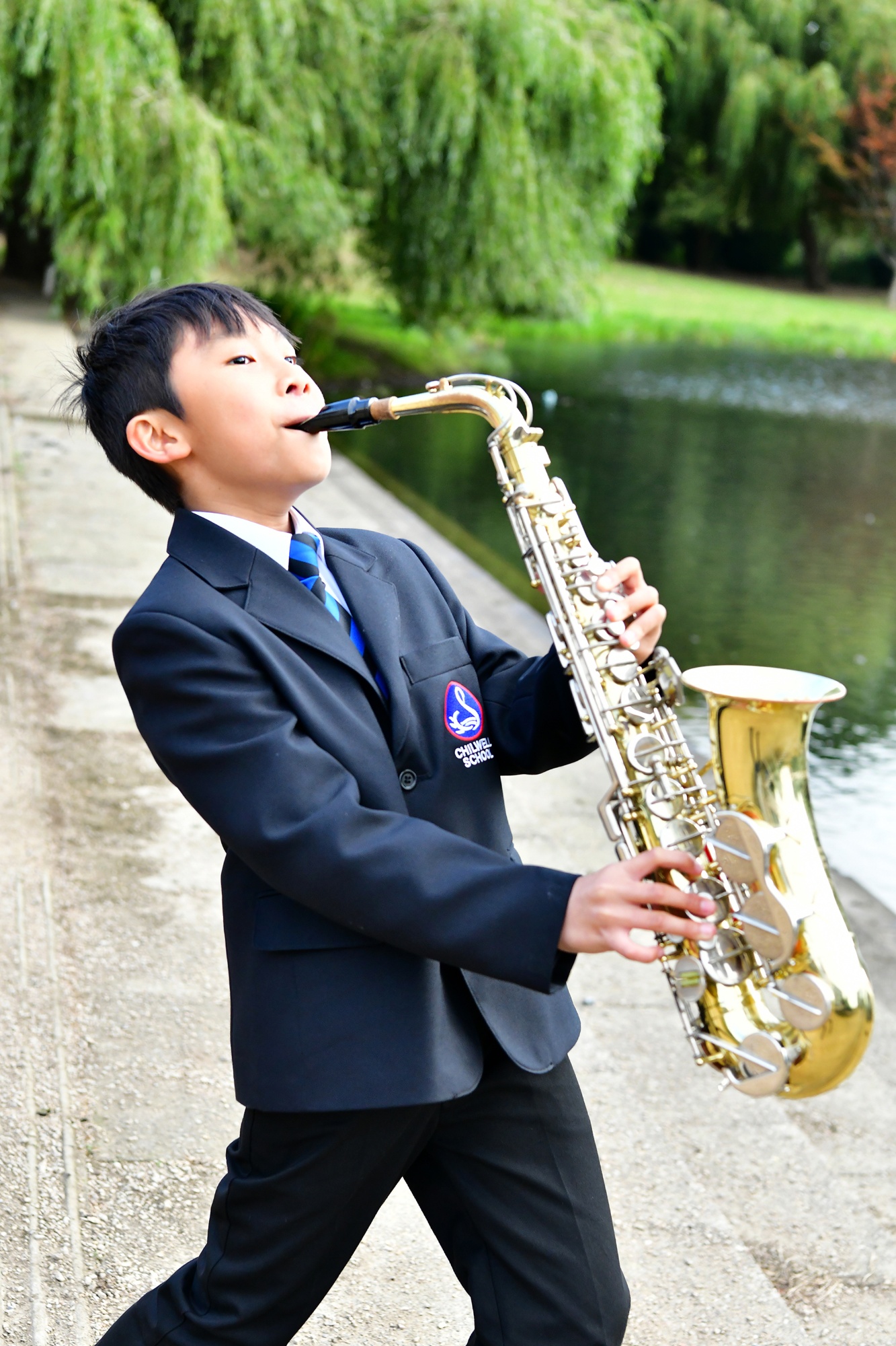 Student playing saxophone by the lake
